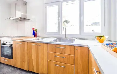 a kitchen with wooden cabinets and a sink and windows at Nice Home In Conil De La Frontera in Conil de la Frontera