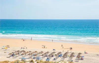 a beach with chairs and umbrellas and the ocean at Nice Home In Conil De La Frontera in Conil de la Frontera