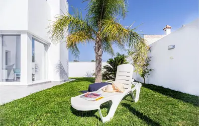a white chair sitting on the grass next to a palm tree at Nice Home In Conil De La Frontera in Conil de la Frontera