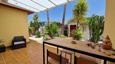 a patio with a table and chairs and palm trees at Sunny villa with private pool in Chiclana de la Frontera in Chiclana de la Frontera
