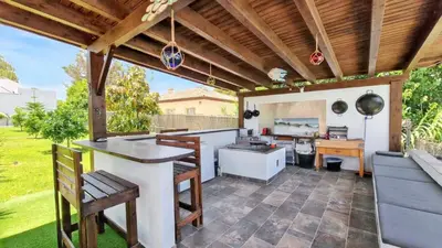 an outdoor kitchen with a wooden pergola at Sunny villa with private pool in Chiclana de la Frontera in Chiclana de la Frontera