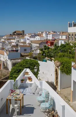 a balcony with tables and chairs and a view of a city at Casa La Muralla in Medina Sidonia