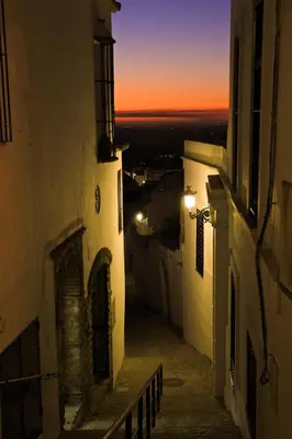 an alley way with buildings and a sunset in the background at Casa La Muralla in Medina Sidonia