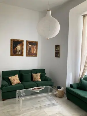 a living room with a green couch and a glass table at Apartamento en el centro in Sanlúcar de Barrameda