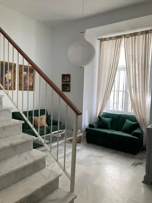a living room with a green couch and stairs at Apartamento en el centro in Sanlúcar de Barrameda
