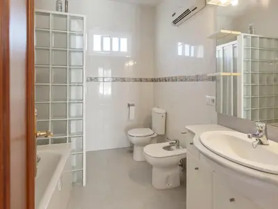 a white bathroom with a toilet and a sink at Costa de la Luz Poolside Villa in Sanlúcar de Barrameda