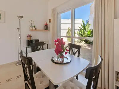 a dining room with a white table and chairs and a window at Costa de la Luz Poolside Villa in Sanlúcar de Barrameda