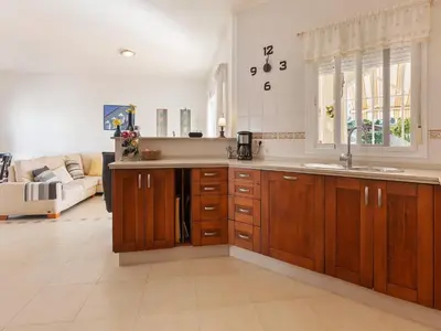 a kitchen with wooden cabinets and a sink and a couch at Costa de la Luz Poolside Villa in Sanlúcar de Barrameda