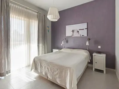 a bedroom with a large bed and a purple wall at Costa de la Luz Poolside Villa in Sanlúcar de Barrameda