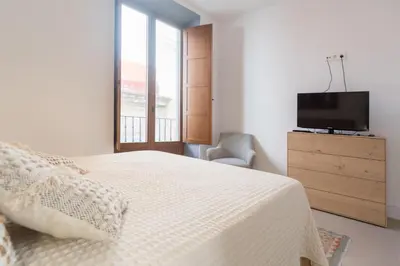 a bedroom with a bed and a dresser with a television at Atico Gades de la Catedral in Cádiz