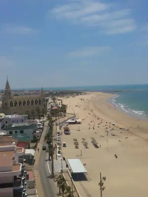 a view of a beach with people and the ocean at Apto Playa de Regla, primera linea, Parking, AA y wifi in Chipiona