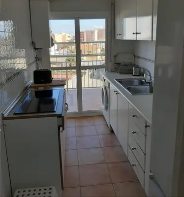 a kitchen with white cabinets and a sink and a window at Apto Playa de Regla, primera linea, Parking, AA y wifi in Chipiona