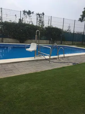 a swimming pool with a white chair next to it at Home Chipiona Cadiz Parking in Chipiona