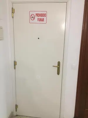 a white door with a prohibited burner sign on it at Home Chipiona Cadiz Parking in Chipiona