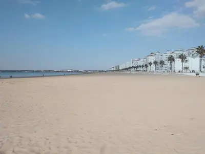 a sandy beach with palm trees and buildings at PRIMERA LINEA DE PLAYA EN VALDELAGRANA in El Puerto de Santa María