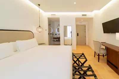 a bedroom with a bed and a desk and a television at Albariza Hotel Boutique in Sanlúcar de Barrameda