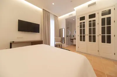 a bedroom with a white bed and a television at Albariza Hotel Boutique in Sanlúcar de Barrameda