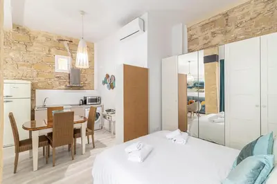 a bedroom with two beds and a table and a kitchen at Allo Apartments Amargura I Centro Loft in Jerez de la Frontera