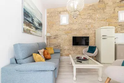 a living room with a blue couch and a stone wall at Allo Apartments Amargura I Centro Loft in Jerez de la Frontera