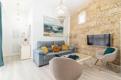 a living room with a blue couch and a stone wall at Allo Apartments Amargura I Centro Loft in Jerez de la Frontera