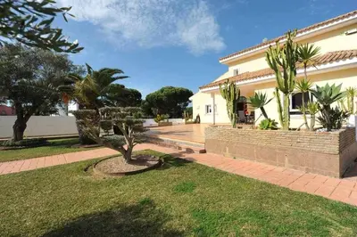 a house with a courtyard with a tree in the yard at Chalet Villa Ventolera Novo Sancti Petri Chiclana in Chiclana de la Frontera