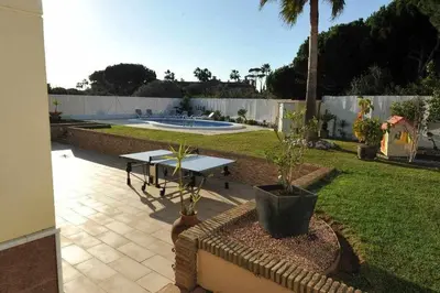 a patio with a table in a yard with a fountain at Chalet Villa Ventolera Novo Sancti Petri Chiclana in Chiclana de la Frontera