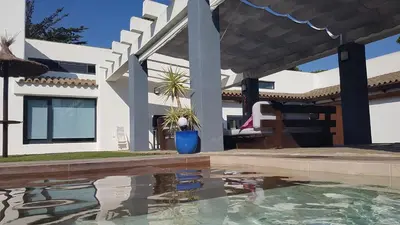 a house with a swimming pool in front of a house at Villa chillout la barrosa in Chiclana de la Frontera
