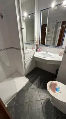 a bathroom with a sink and a toilet and a mirror at Apartamento en La Almadraba in Chiclana de la Frontera