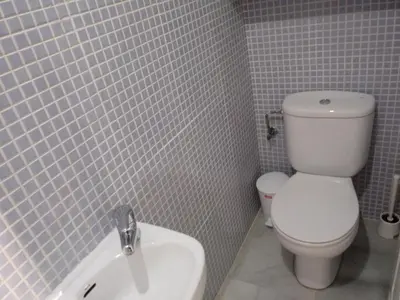 a bathroom with a white toilet and a sink at Apartamento Rotasol in Rota