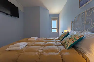 a bedroom with a large bed with pillows and a television at GAVIOTA Family Home free parking by Cadiz4Rentals in Cádiz