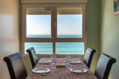 a dining room table with chairs and a large window at GAVIOTA Family Home free parking by Cadiz4Rentals in Cádiz