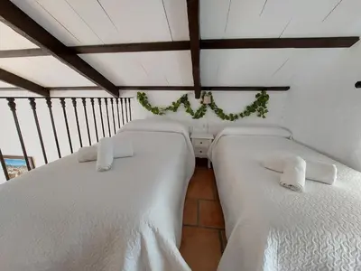 two beds in a room with white sheets at Villa El Estanque Holiday Cottage & Bungalow in Arcos de la Frontera