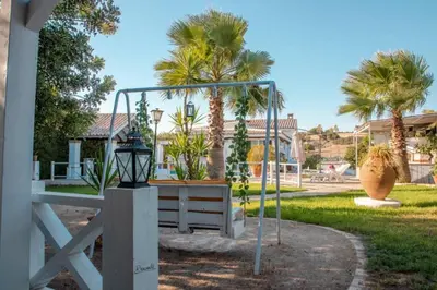 a swing in a yard with palm trees at Villa El Estanque Holiday Cottage & Bungalow in Arcos de la Frontera