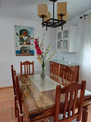 a dining room table with a vase of flowers on it at Villa El Estanque Holiday Cottage & Bungalow in Arcos de la Frontera