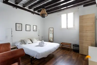 a bedroom with a large white bed and wooden floors at Diana de Columela by Cadiz Time in Cádiz