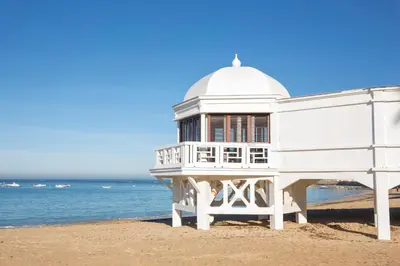 a white building on the beach next to the ocean at Apartamento Cádiz Centro Blue Window in Cádiz