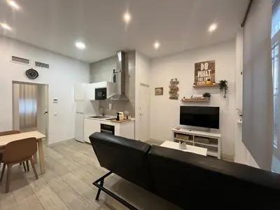 a living room with a couch and a tv and a table at Rinconcito del Falla Grupo AC Gestion in Cádiz