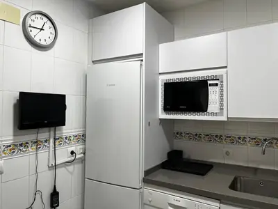 a kitchen with a refrigerator and a clock on the wall at Las Gemelas de Benjumeda en la Caleta Grupo AC Gestion in Cádiz