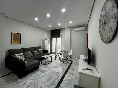 a living room with a couch and a clock on the wall at Las Gemelas de Benjumeda en la Caleta Grupo AC Gestion in Cádiz