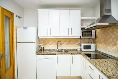 a kitchen with white cabinets and a sink and a refrigerator at VALDECARRETAS Apartamento Rota cerca de playa in Rota