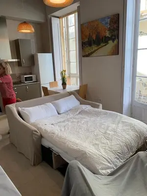 a large bed in a room with a woman in a kitchen at Apartamentos Valverde Cádiz 1 - A in Cádiz
