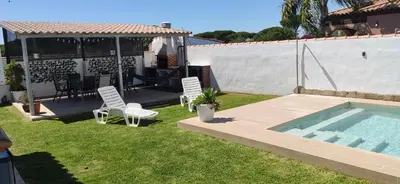 a backyard with a pool and chairs and a house at Chalet Santi Playa de la Barrosa in Chiclana de la Frontera