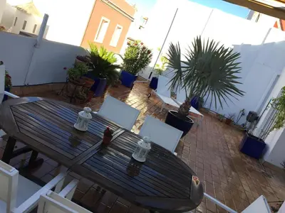 a wooden table and chairs on a patio with plants at La terraza de San Pedro in Cádiz