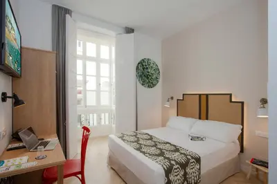 a bedroom with a bed and a desk with a laptop at Casual con Duende Cadiz in Cádiz