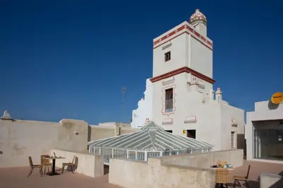 a building with a tower with tables and chairs at Casual con Duende Cadiz in Cádiz