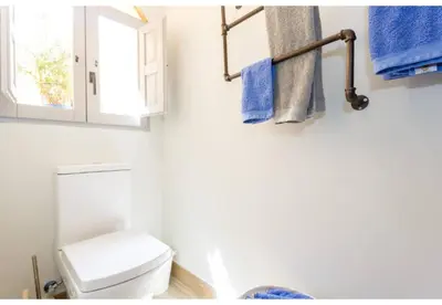 a bathroom with a toilet and a window and blue towels at TERRAZA-Caleta Beach Home by Cadiz4Rentals in Cádiz