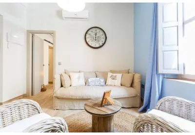 a living room with a couch and a clock on the wall at PATIO-Caleta Beach Home by Cadiz4Rentals in Cádiz