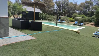 a swimming pool with a blue hose on the grass at Casa Rural El Romeral in Medina Sidonia