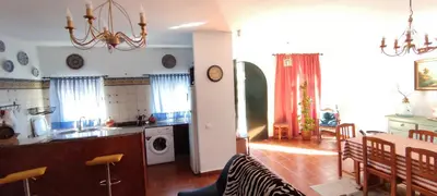 a kitchen and living room with a table and a dining room at Casa Rural El Romeral in Medina Sidonia