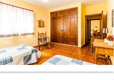 a bedroom with two beds and a table and a desk at Casa Rural El Romeral in Medina Sidonia